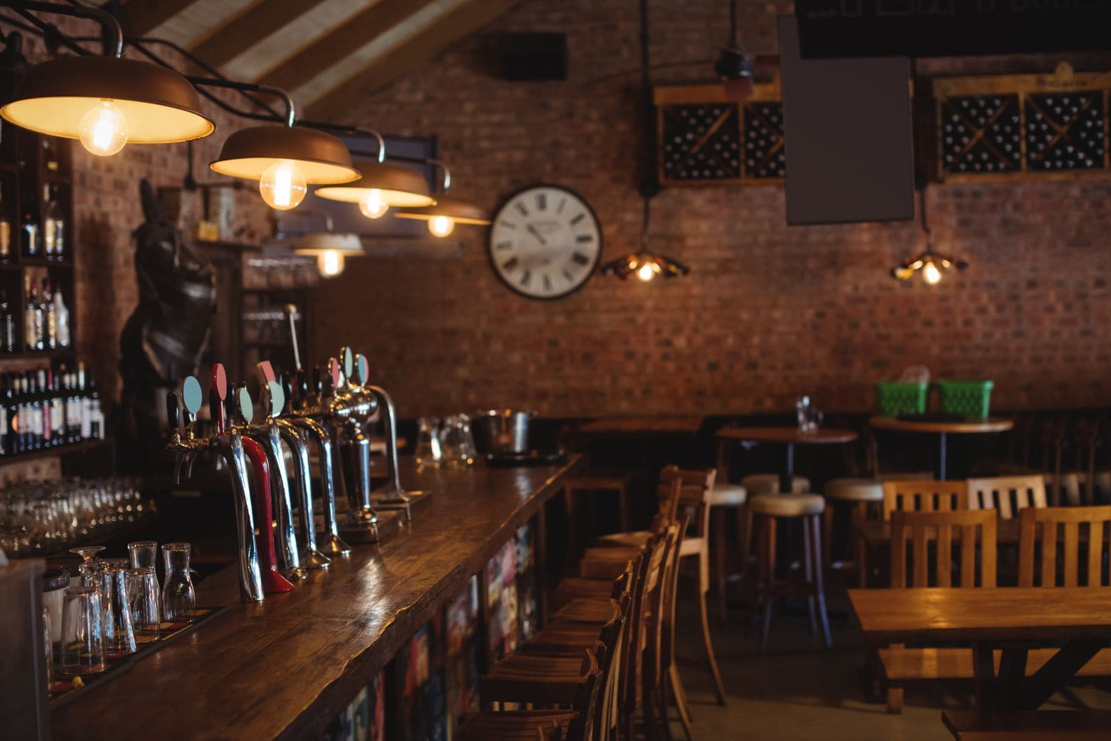 Barra de bar terminada con tiradores de cerveza, sobre de madera y pared de ladrillo visto