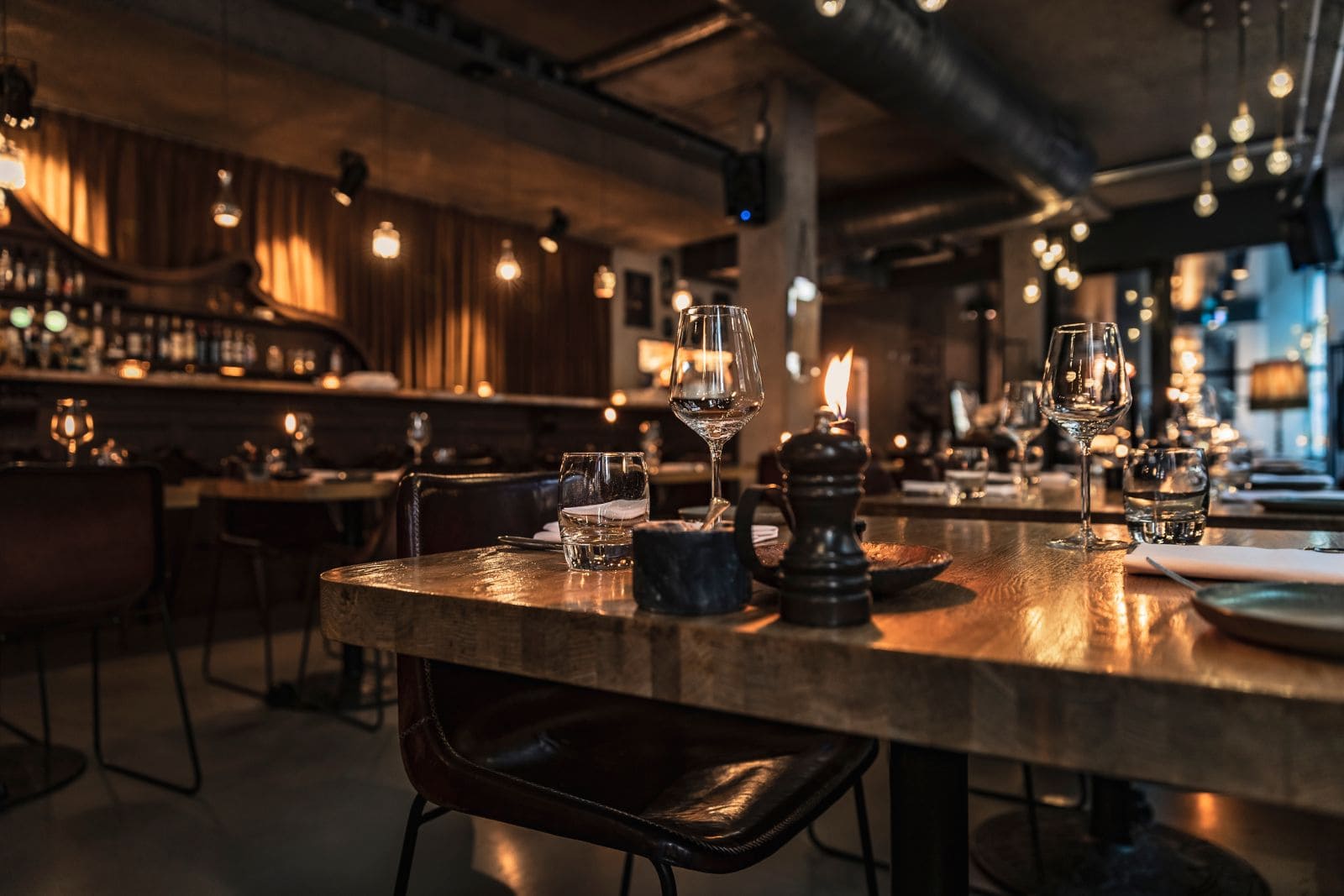 Comedor de restaurante reformado con techo técnico visto y barra al fondo
