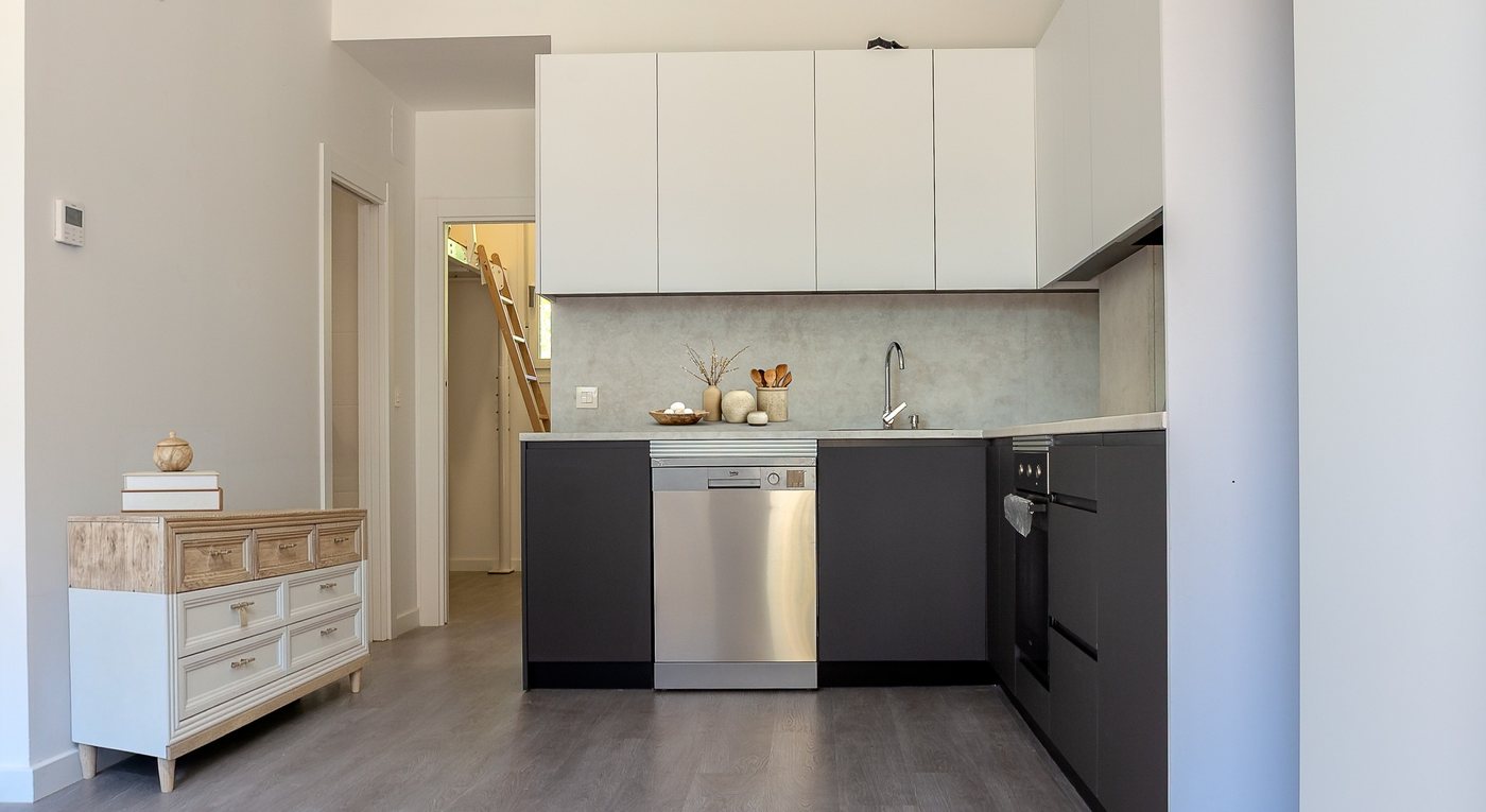 Cocina con muebles altos blancos, bajos en gris grafito y lavavajillas de acero