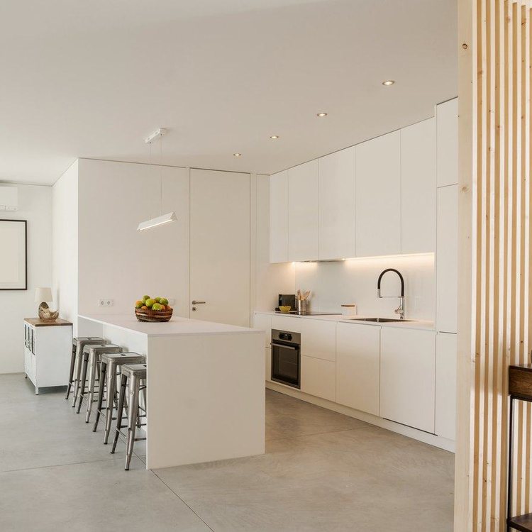 Cocina blanca con frentes sin tiradores e isla con taburetes