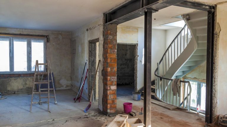 Interior de una vivienda de Zaragoza a medio reformar, con los tabiques picados, vigas metálicas y herramientas de obra