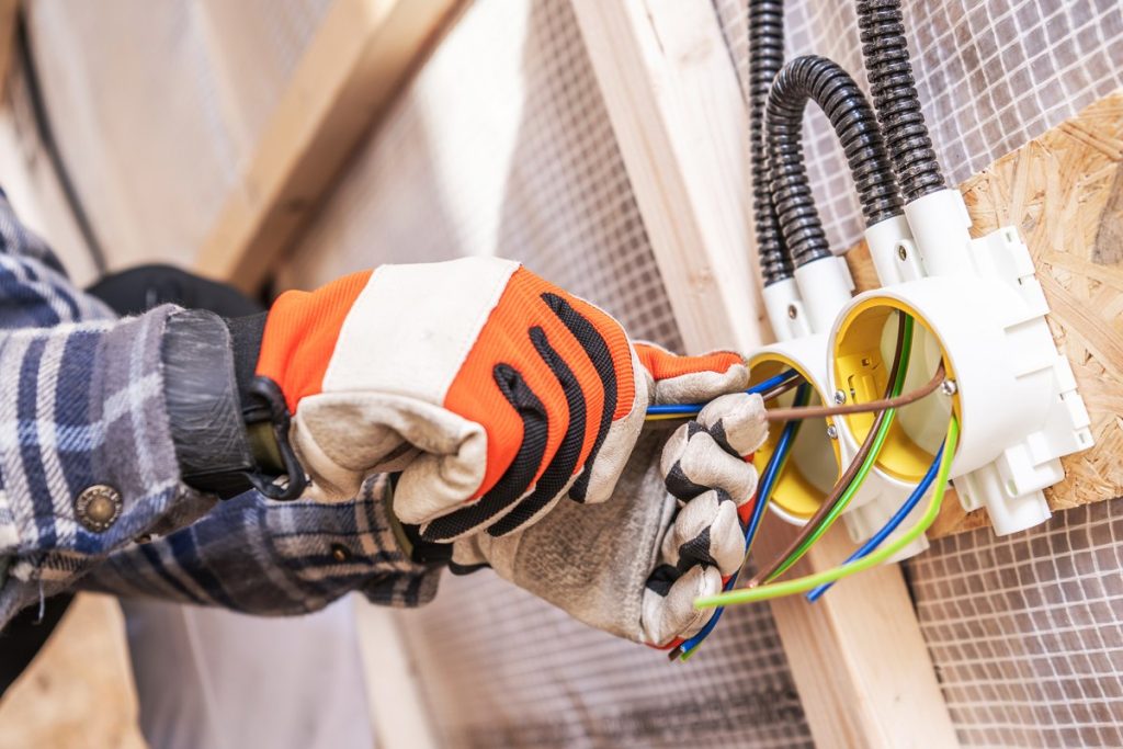 Electricista conectando los cables nuevos en las cajas de mecanismos de un tabique durante una reforma