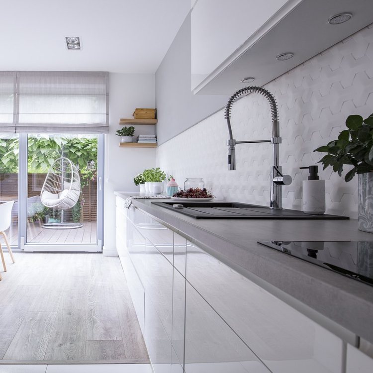 Fregadero con grifo de muelle en una cocina blanca con encimera gris