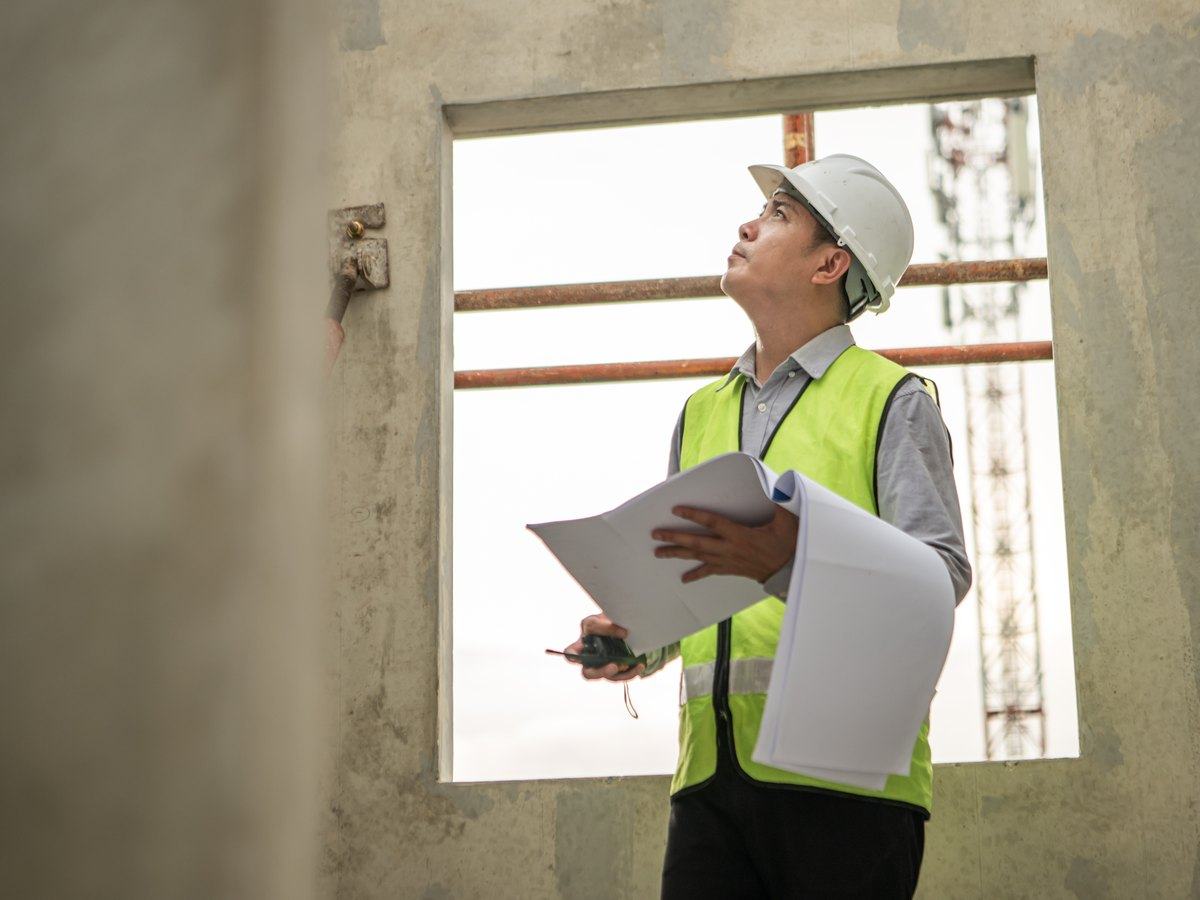 Técnico con casco revisando una vivienda en obra sin acabar antes de redactar el proyecto
