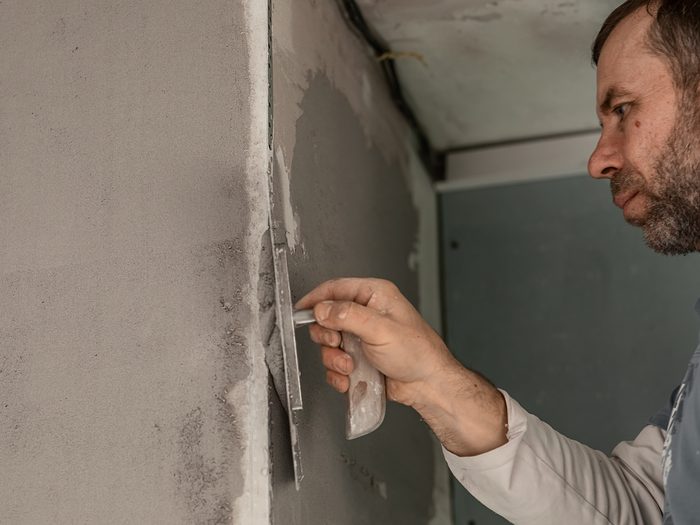 Operario enyesando con la llana una pared de una vivienda en obra