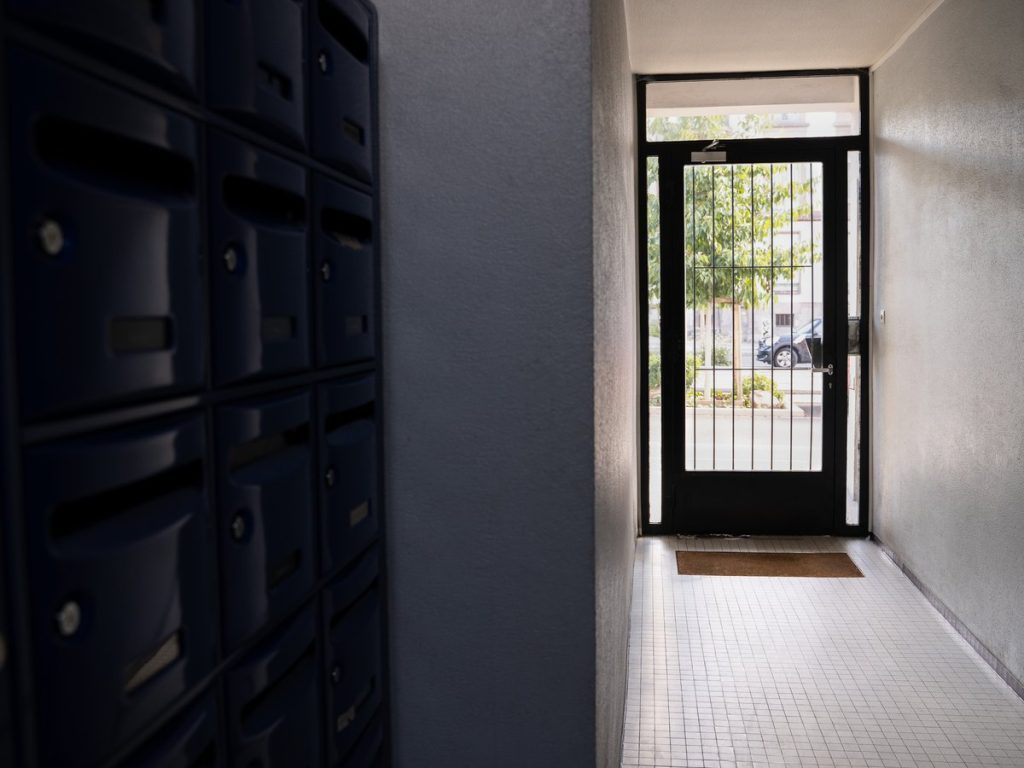 Portal de una comunidad de vecinos con los buzones y la puerta a la calle