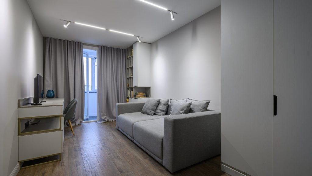 Salón de un piso reformado en Zaragoza con suelo laminado, luz en carriles en el techo y armario empotrado