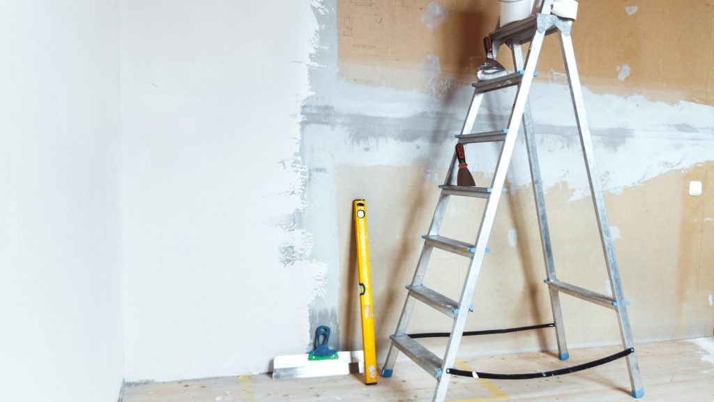 Escalera de tijera, nivel y espátula en una habitación durante una reforma económica en Zaragoza