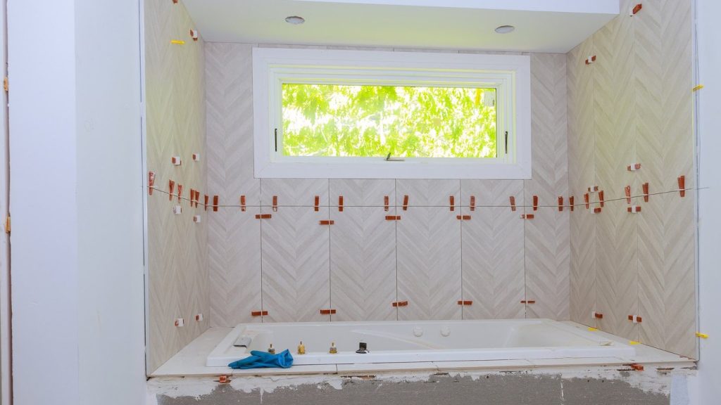 Alicatado en espiga a media obra sobre la bañera durante una reforma parcial de baño en Zaragoza