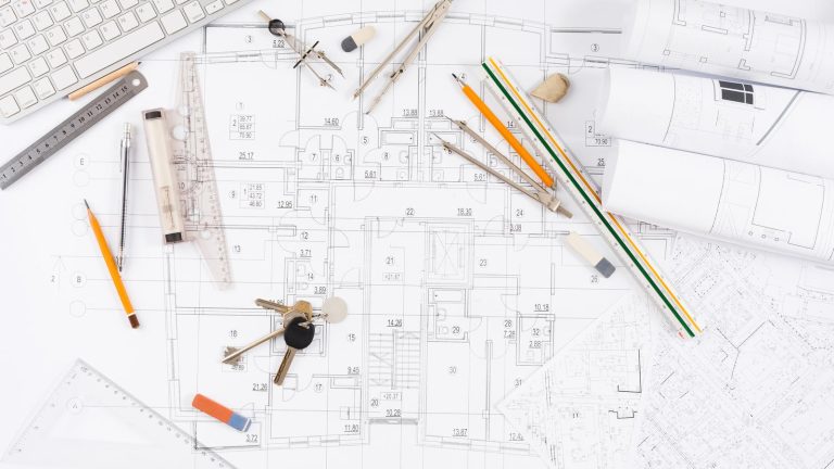 Plano acotado de una vivienda con escalas, compás y llaves sobre la mesa, la documentación de una licencia de obra