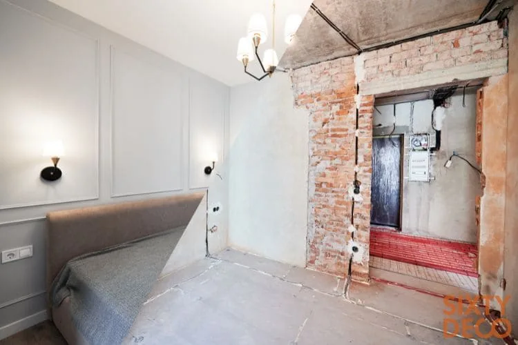 Dormitorio partido en dos: cama y paredes con molduras junto al hueco de ladrillo y el suelo radiante en obra, albañilería profesional Zaragoza
