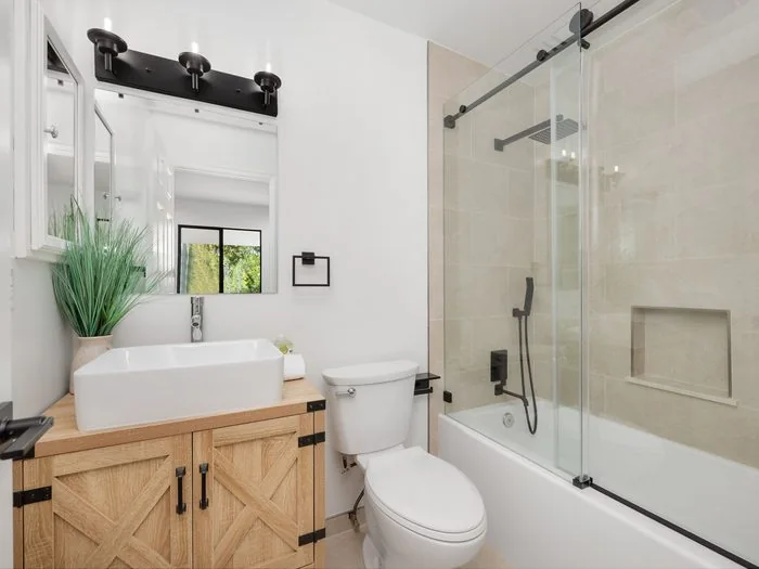 Baño pequeño con mueble de lavabo de madera, espejo, inodoro y bañera con mampara corredera, baños pequeños bonitos Zaragoza