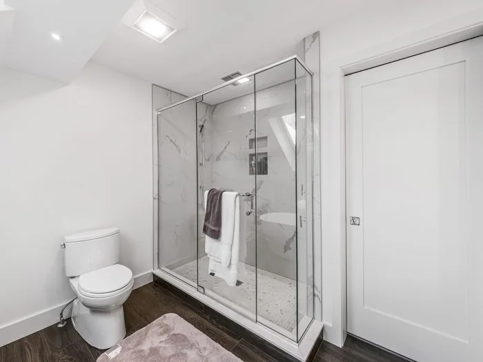 Baño blanco con ducha de mampara de vidrio y plato a ras de suelo junto al inodoro, cambiar bañera por ducha precio Zaragoza