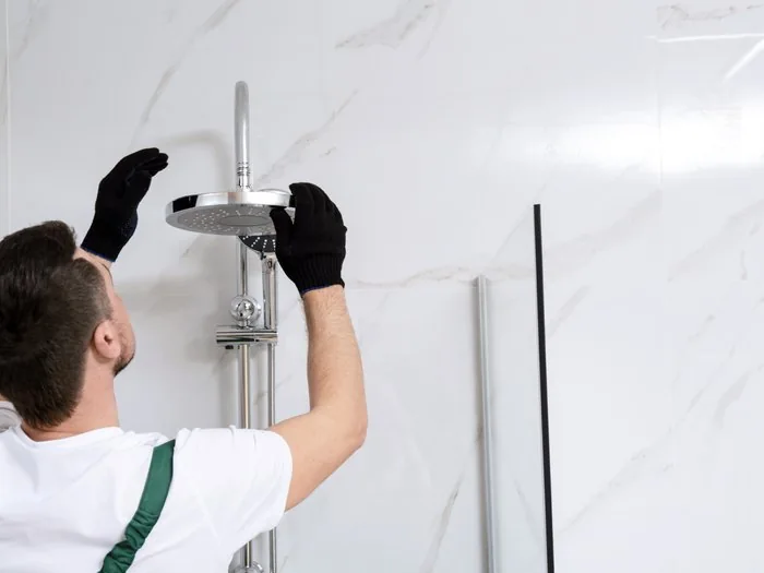 Técnico instalando la columna de ducha en la pared alicatada de un baño, cambio bañera por ducha Zaragoza