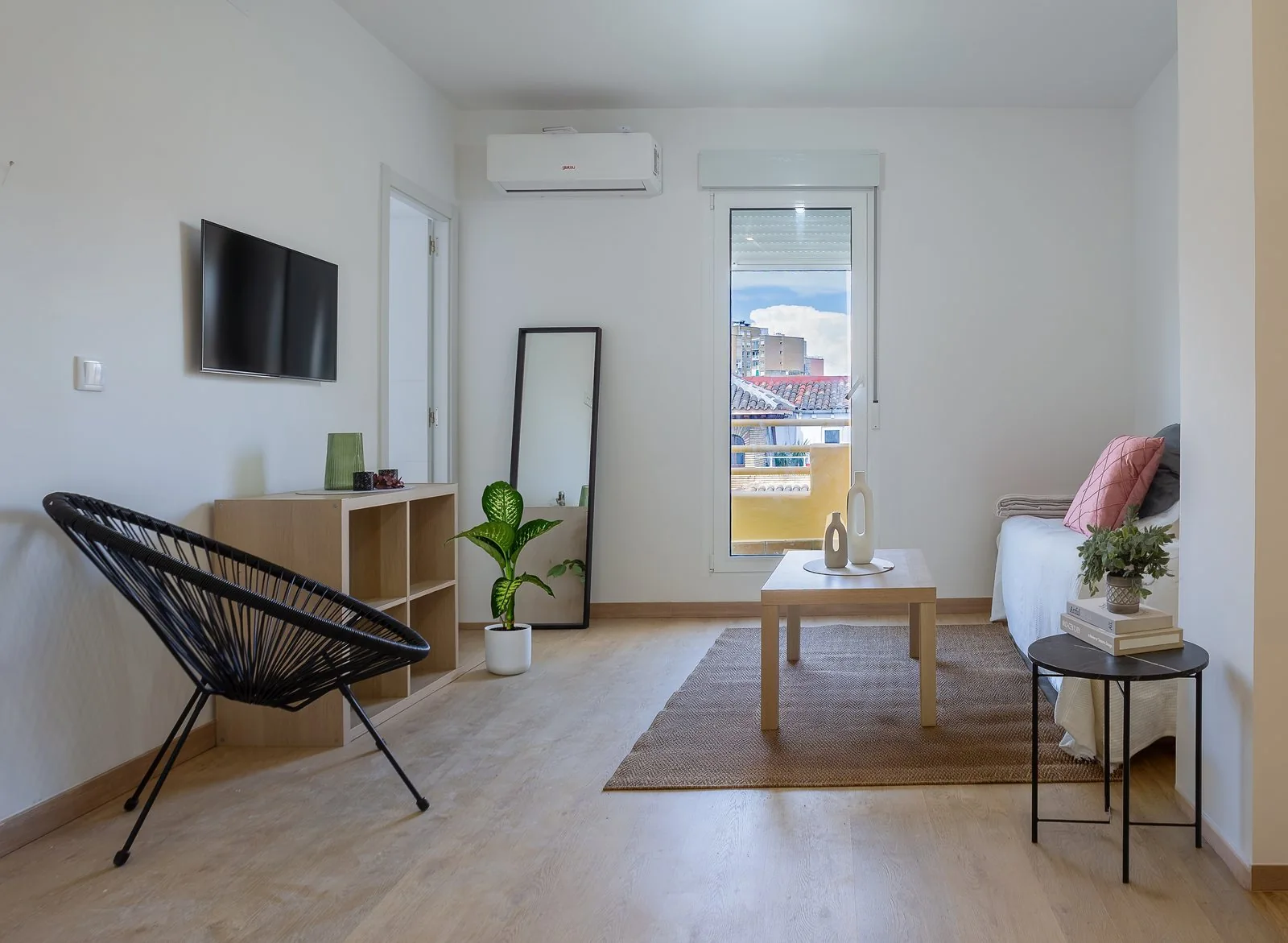 Salón reformado con suelo de madera clara y luz natural entrando por la puerta del balcón, comprar reformar y alquilar Zaragoza