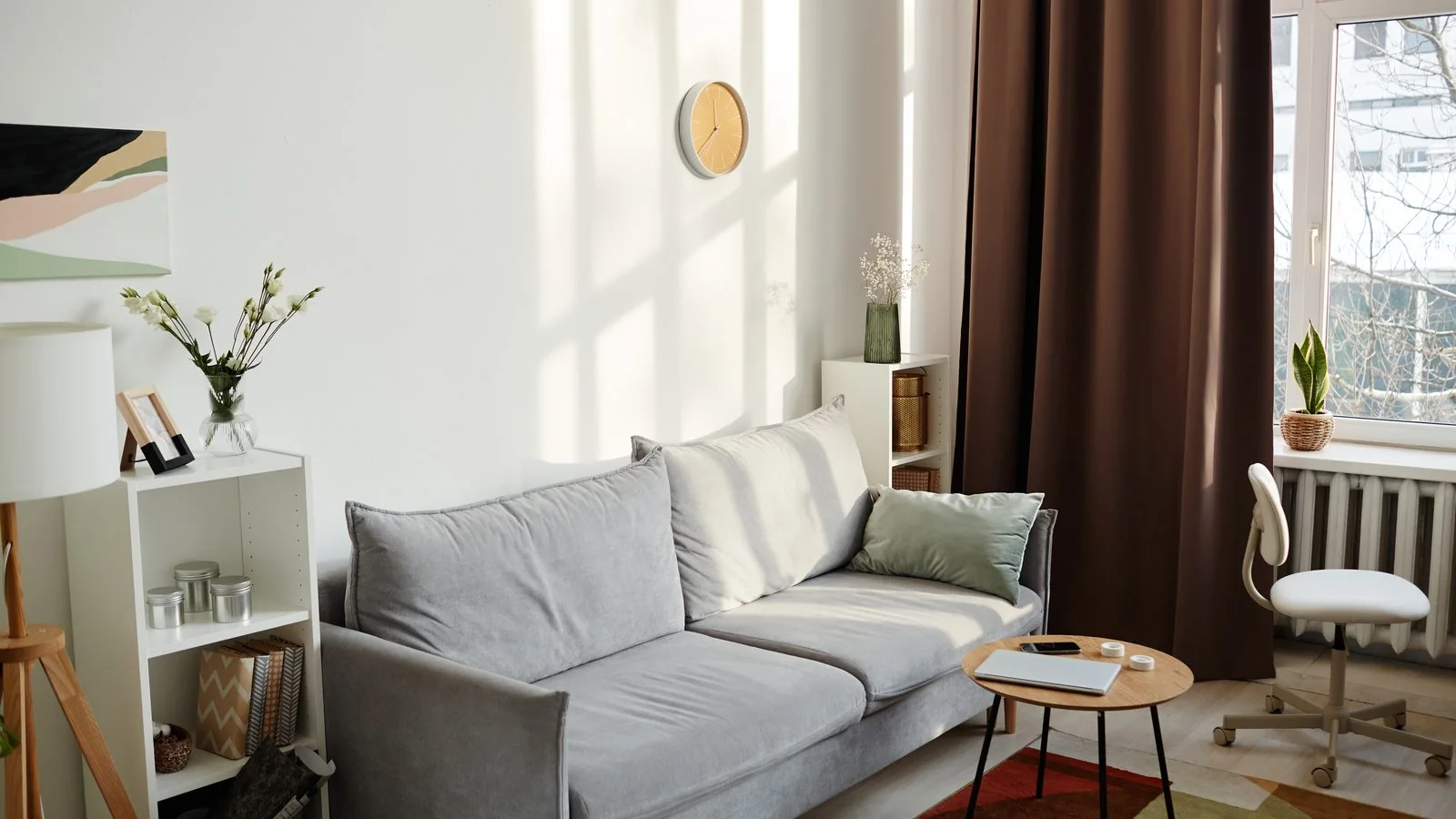 Salón de un piso reformado con sofá gris, suelo de tarima, paredes claras y ventana con cortinas, cuánto cuesta reformar una casa Zaragoza
