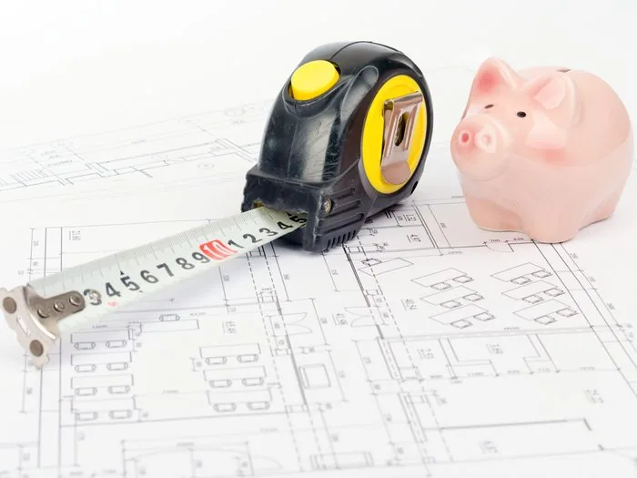 Cinta métrica y hucha sobre el plano de una vivienda, cuánto cuesta una reforma integral en Zaragoza