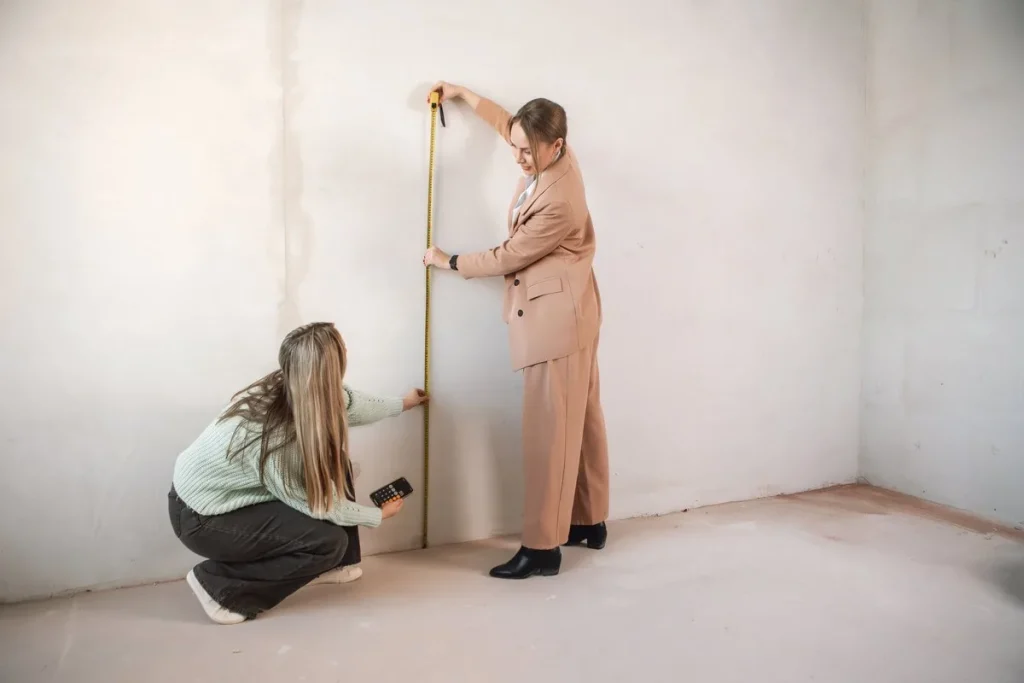 Dos personas toman con un metro las medidas de la pared de una estancia vacía, estudio de cocinas Zaragoza