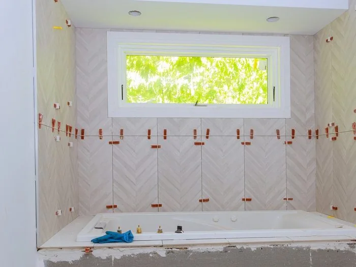 Baño en obra alicatado en espiga blanca con niveladores alrededor de la bañera, precio azulejo baño Zaragoza