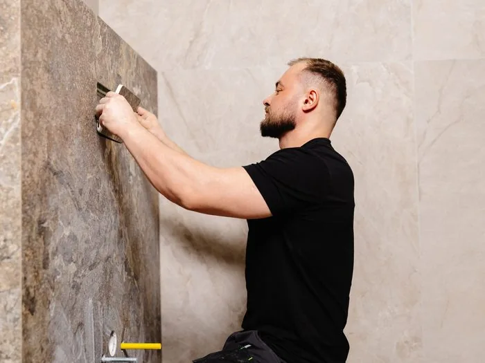 Alicatador colocando una pieza de porcelánico de gran formato en la pared, precio m2 alicatado de paredes Zaragoza