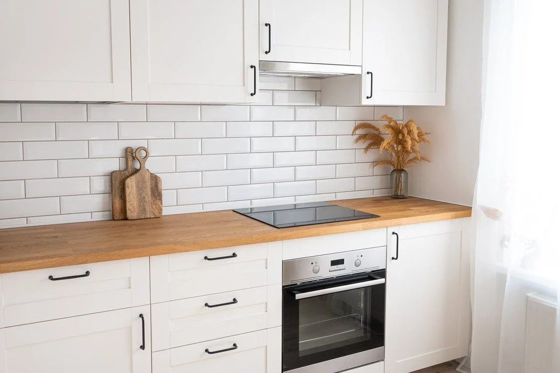 Cocina con placa de inducción, azulejo blanco biselado y encimera de madera, precio reforma integral cocina 15m2 Zaragoza