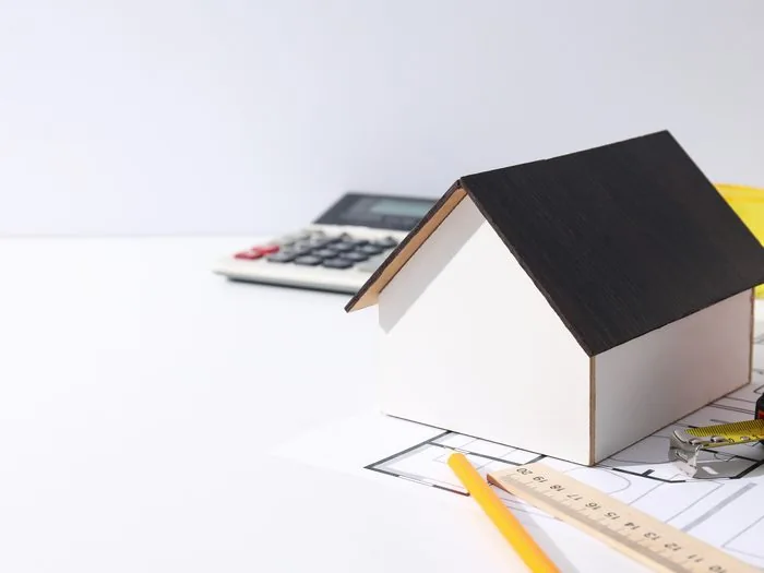 Maqueta de una casa sobre el plano de un piso, con calculadora, lápiz y regla, presupuesto reforma casa de 90 metros cuadrados Zaragoza