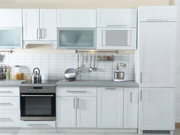Cocina blanca con horno en columna, frigorífico integrado y frente de azulejo, presupuesto reforma cocina Zaragoza
