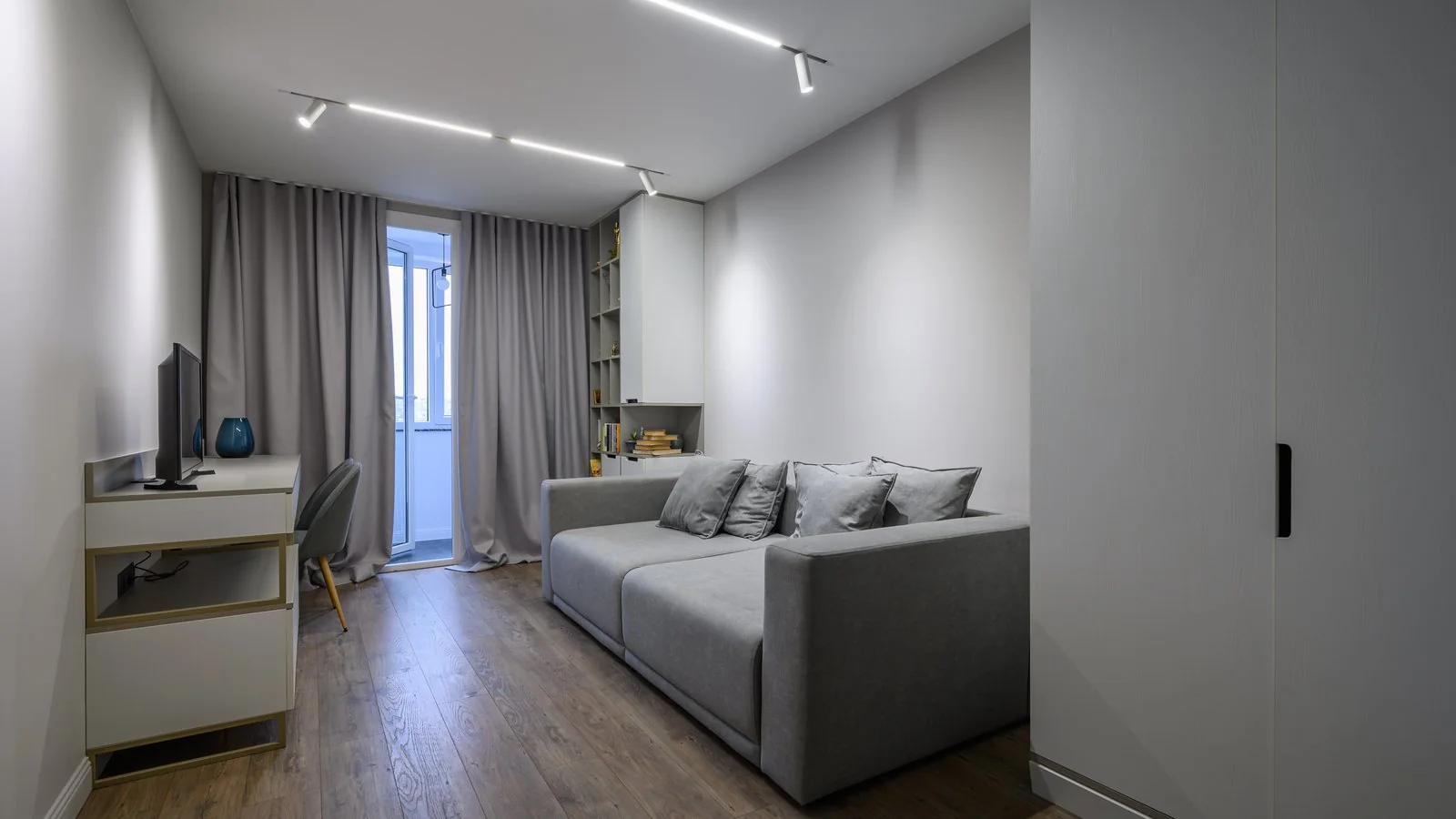 Salón reformado con sofá gris, suelo laminado, luz en carriles en el techo y armario empotrado, presupuesto reformas Zaragoza