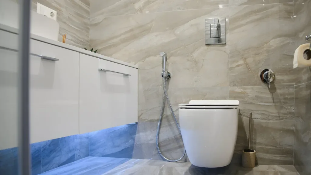 Inodoro suspendido con ducha higiénica, mueble suspendido blanco con luz LED y porcelánico imitación mármol, reforma baño precio Zaragoza
