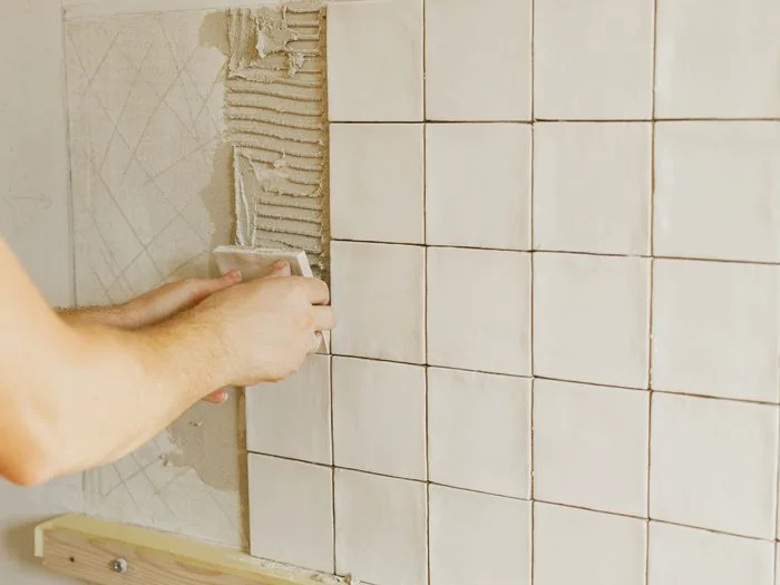 Azulejo blanco recién colocado sobre cemento cola peinado en la pared de un baño, reforma baños presupuesto Zaragoza