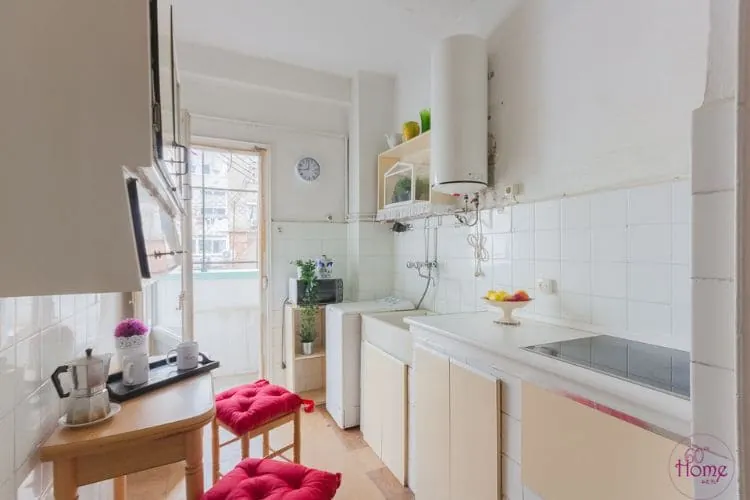 Cocina antigua antes de la reforma, con azulejo blanco y termo en la pared, reforma de piso completo Zaragoza