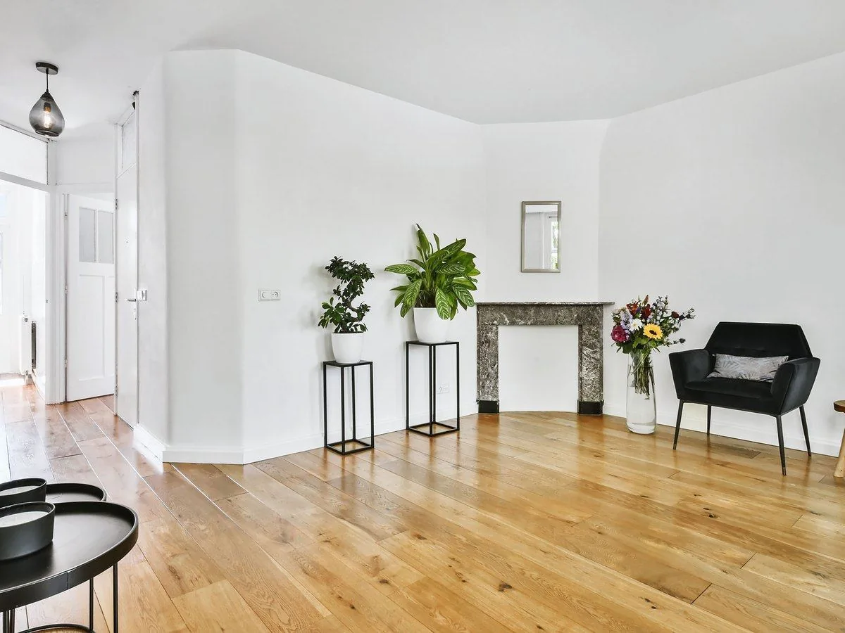 Salón reformado con tarima de roble, paredes blancas y chimenea de mármol, reforma de piso Zaragoza