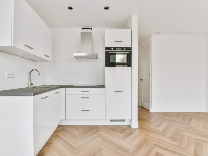 Cocina blanca en L con columna de horno y suelo de espiga, reforma piso para alquilar Zaragoza