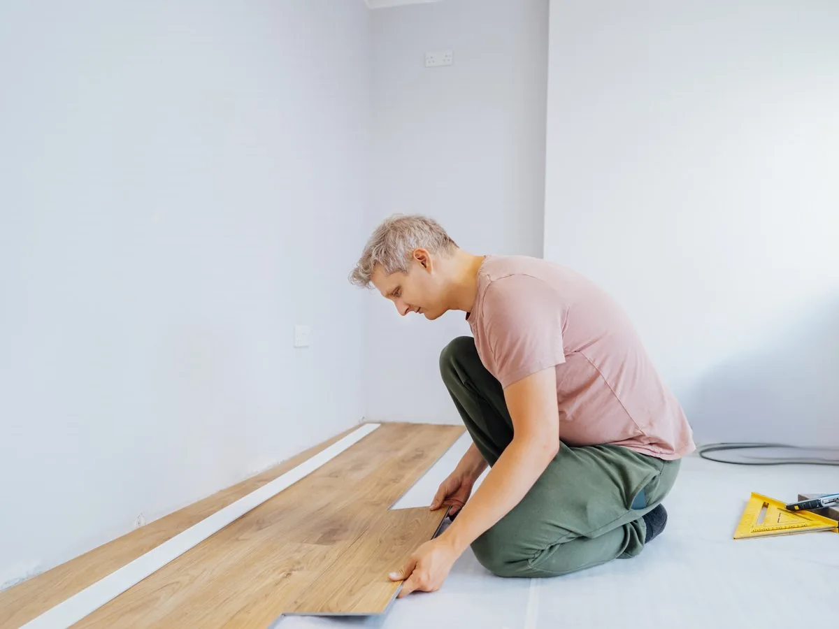 Operario colocando el suelo laminado en una habitación de paredes blancas, reformar vivienda precio Zaragoza