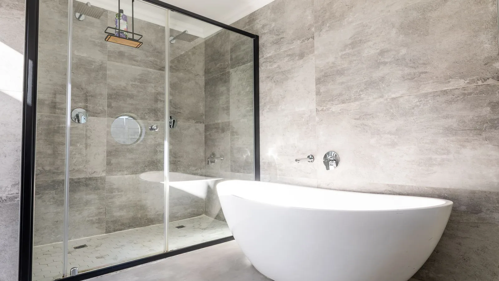 Ducha de obra con mampara de cristal, bañera exenta y paredes de porcelánico gris de gran formato, reformas baño Zaragoza
