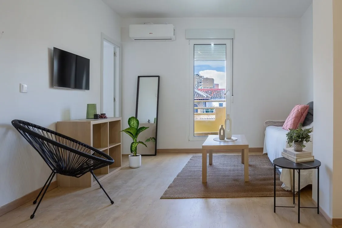 Salón reformado con suelo de madera clara, aire acondicionado y salida al balcón, reformas de lujo Zaragoza